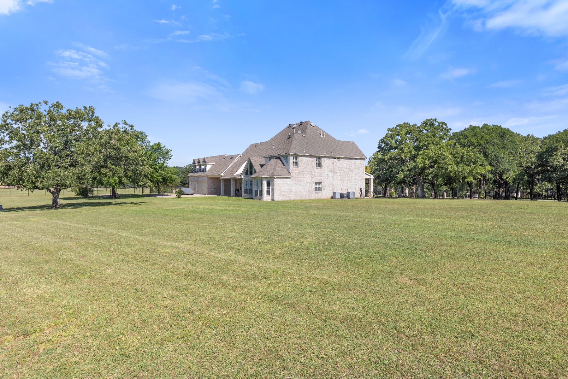 Rear elevation framed by mature oaks