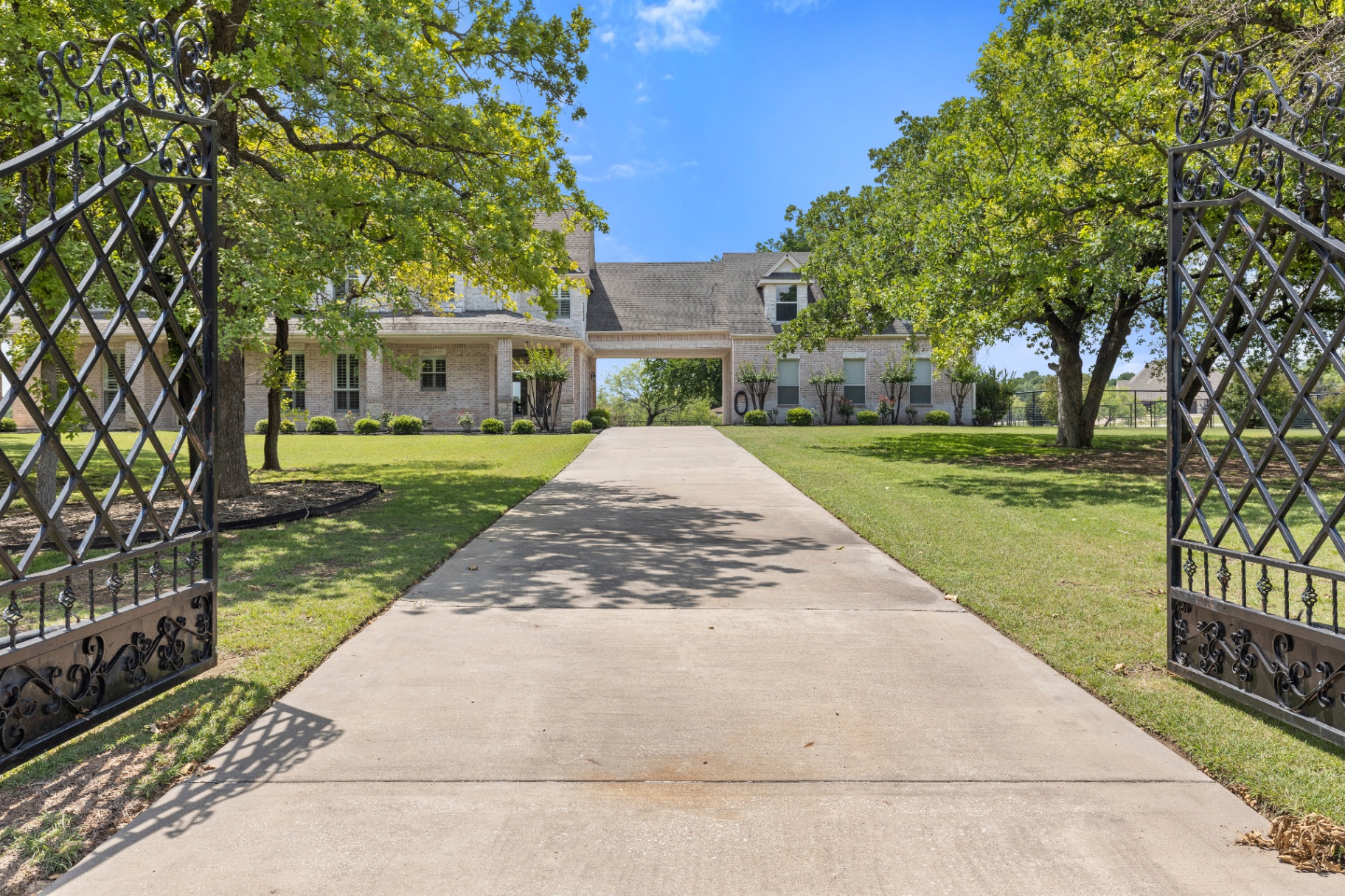 Open wrought iron gates framing the driveway